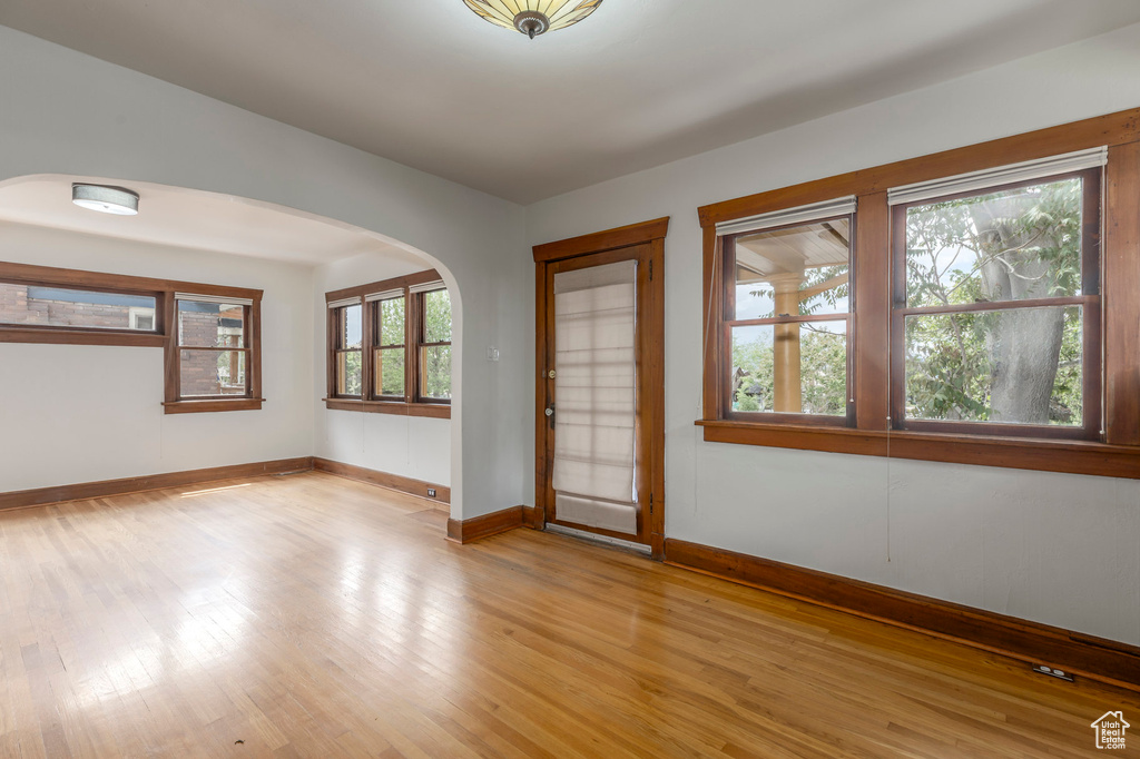 Spare room with light wood-style flooring, baseboards, and arched walkways