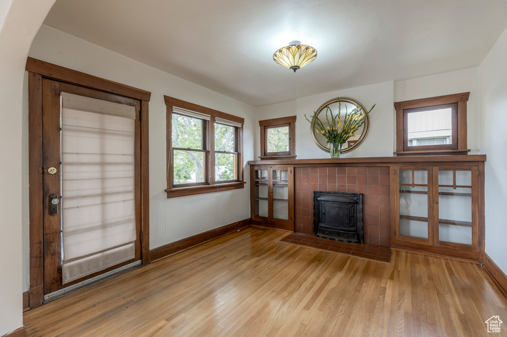 Unfurnished living room with a wood stove, light wood finished floors, and baseboards