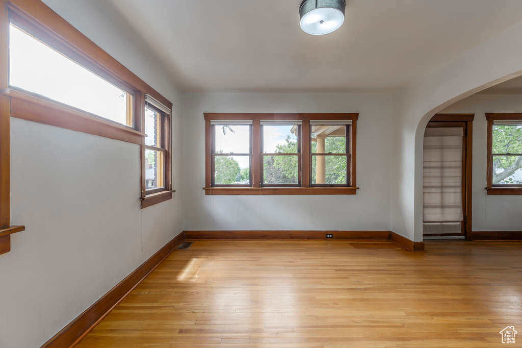 Spare room with light wood-style flooring, baseboards, and arched walkways
