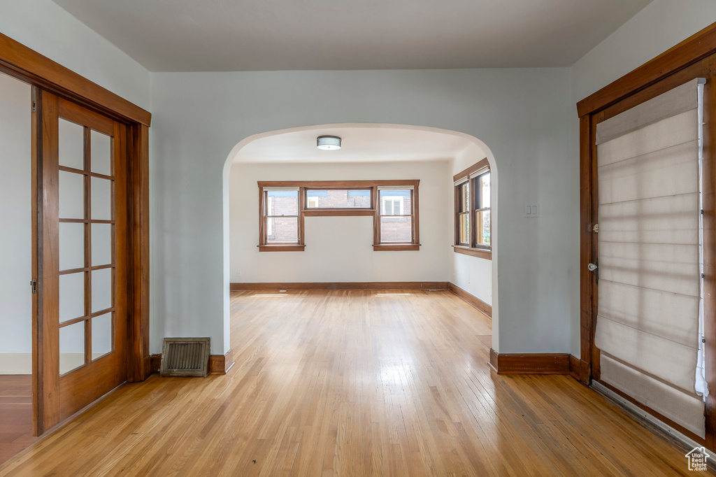Unfurnished room with light wood-style floors, arched walkways, and baseboards
