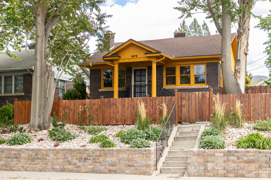 Bungalow-style house with a chimney, a fenced front yard, and brick siding