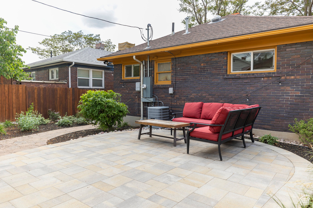 View of patio with outdoor lounge area, central air condition unit, and fence