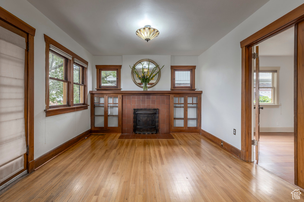Unfurnished living room featuring a wood stove, light wood-style floors, baseboards, and healthy amount of natural light