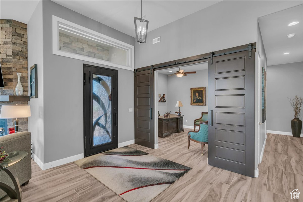 Foyer entrance with a barn door, baseboards, light wood-type flooring, and recessed lighting