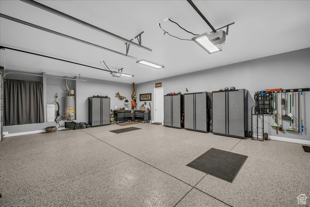 Garage with water heater, a garage door opener, and baseboards