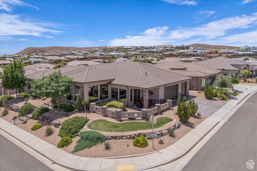 View of front of house with concrete driveway, an attached garage, a residential view, a tile roof, and a mountain view