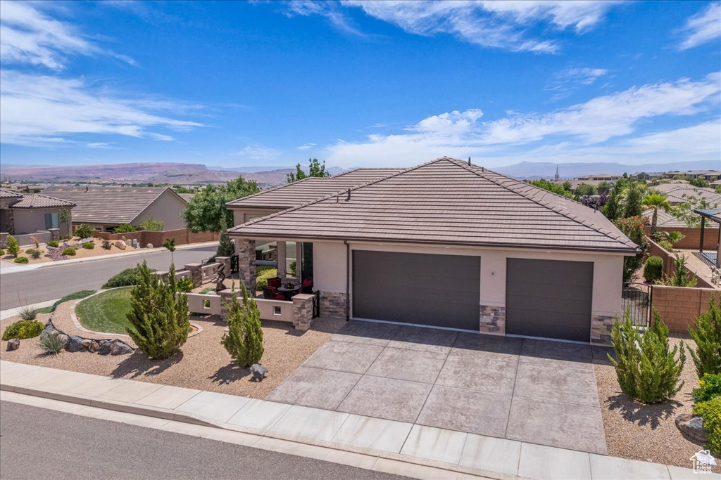 Single story home with stone siding, driveway, a mountain view, and stucco siding