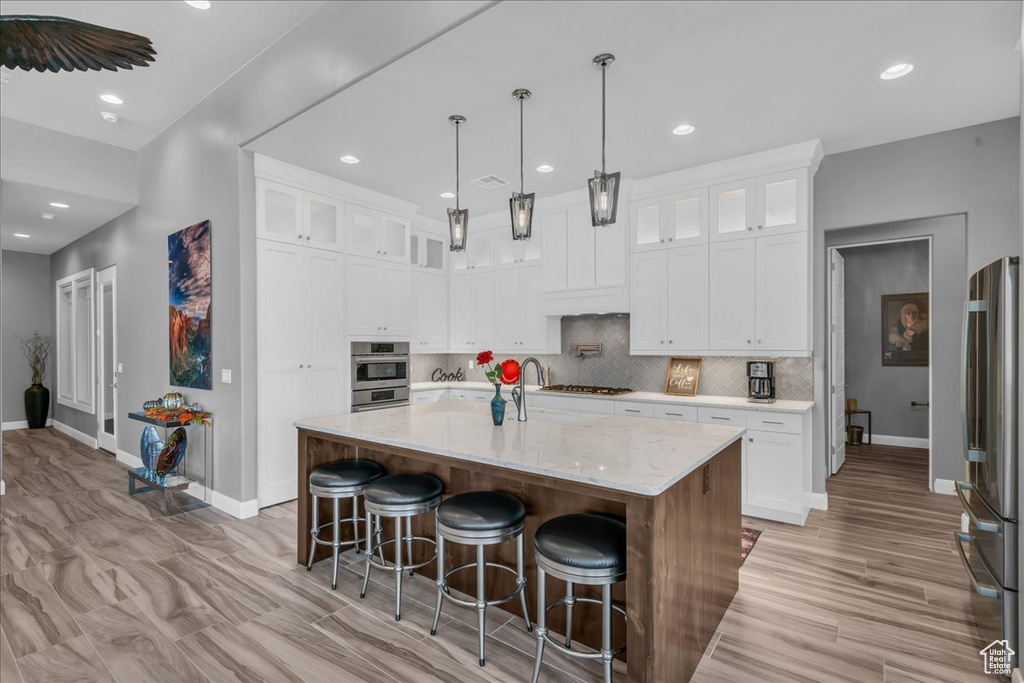 Kitchen featuring stainless steel appliances, baseboards, recessed lighting, backsplash, and white cabinets