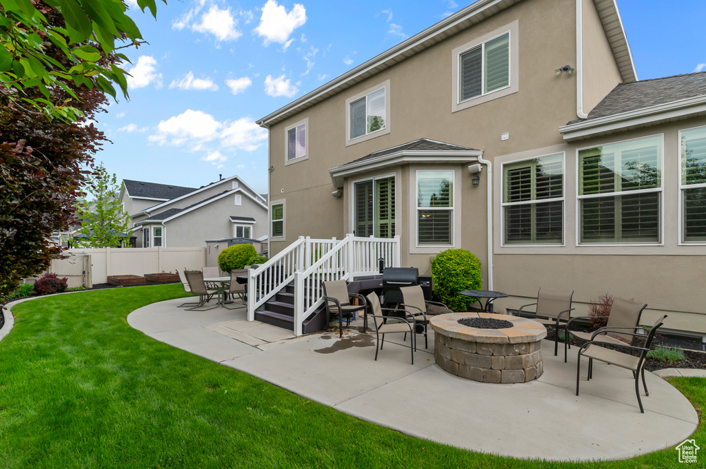 Back of property with stucco siding, a patio, and a fire pit