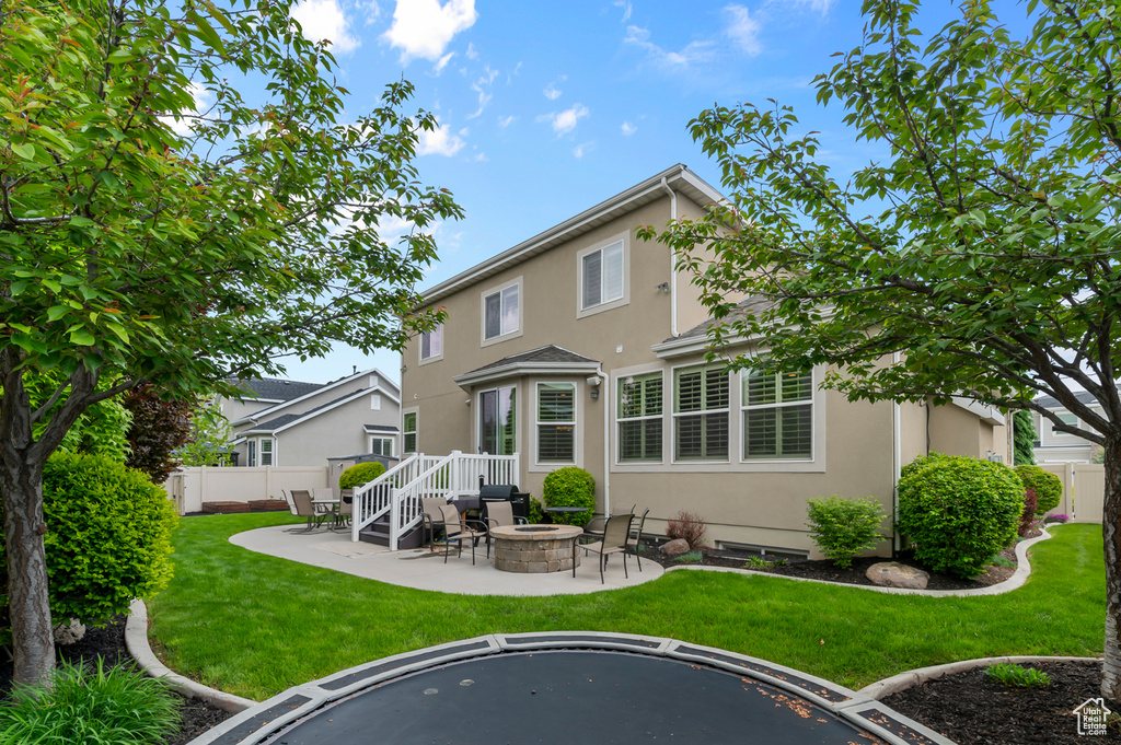 Back of house featuring a fire pit, stucco siding, and a patio area