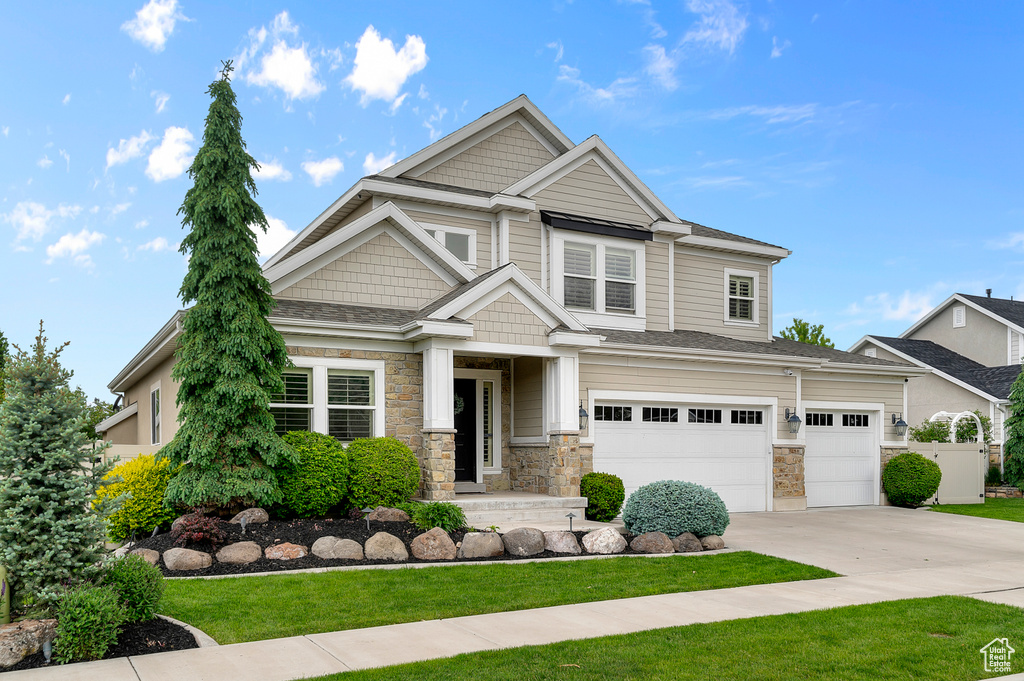 Craftsman inspired home with stone siding, driveway, and an attached garage