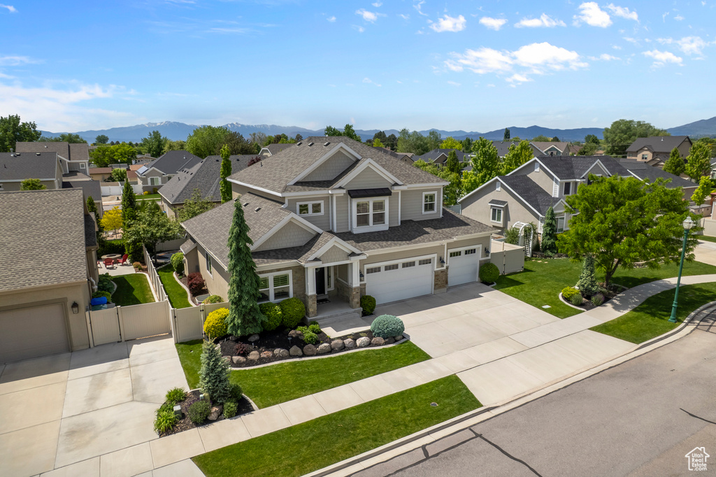 View of front of home featuring a residential view, driveway, a gate, stone siding, and a mountain view