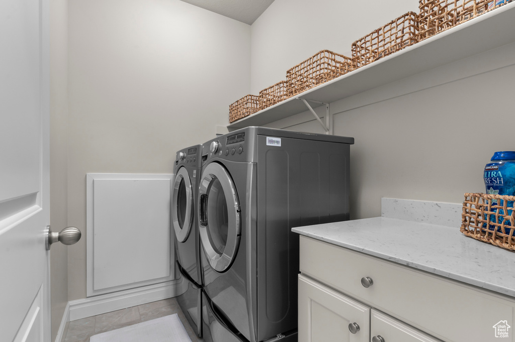 Clothes washing area featuring washer and dryer, light tile patterned flooring, and baseboards