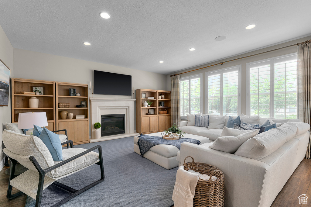Living room with recessed lighting, a textured ceiling, a glass covered fireplace, and dark wood finished floors