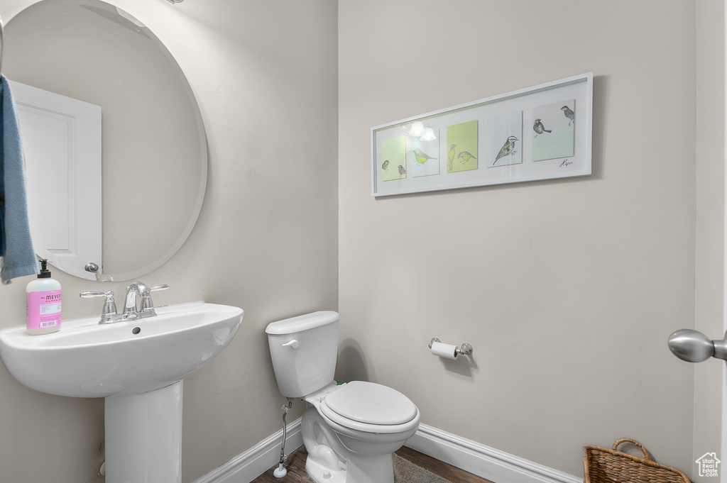 Half bathroom featuring baseboards, toilet, and a sink