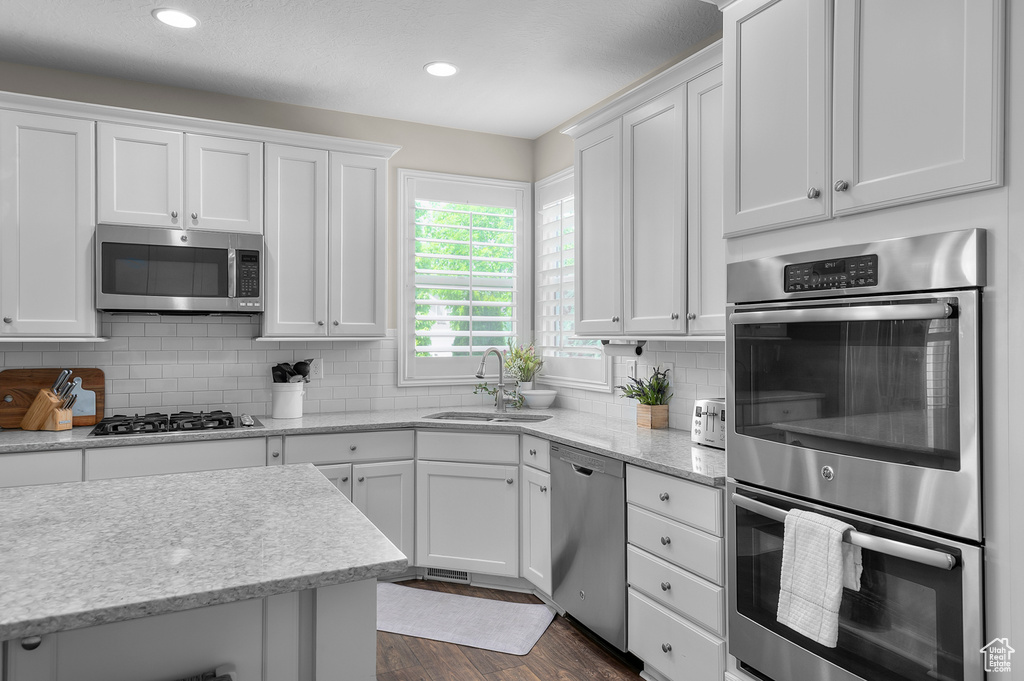 Kitchen featuring appliances with stainless steel finishes, a sink, white cabinets, backsplash, and recessed lighting
