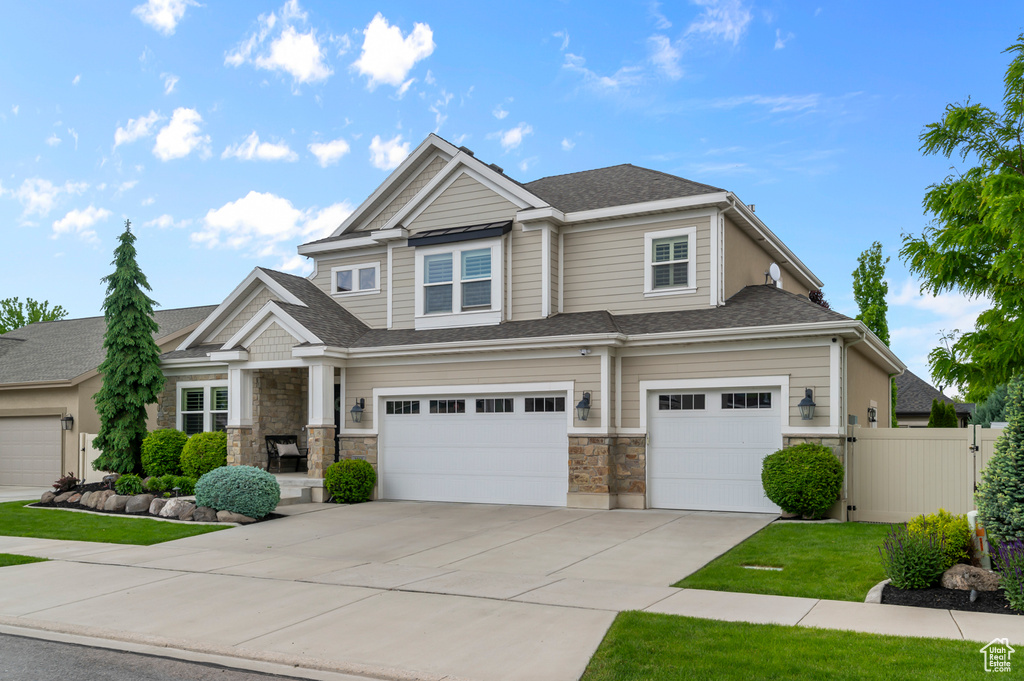 Craftsman inspired home featuring an attached garage, driveway, stone siding, and a shingled roof