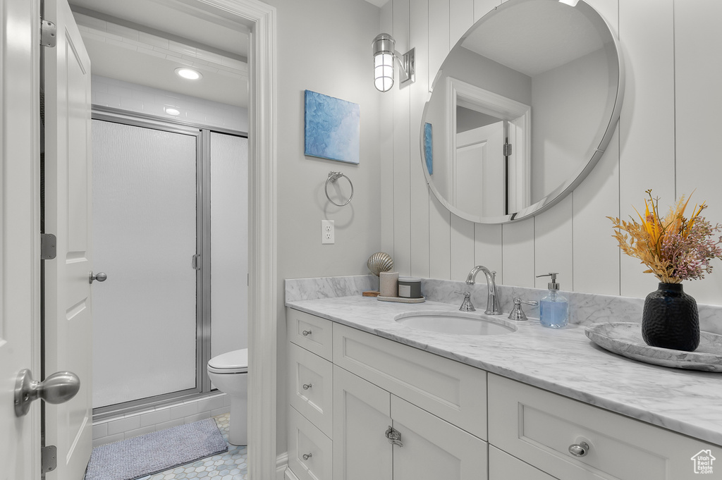 Full bath featuring vanity, a stall shower, toilet, and tile patterned floors