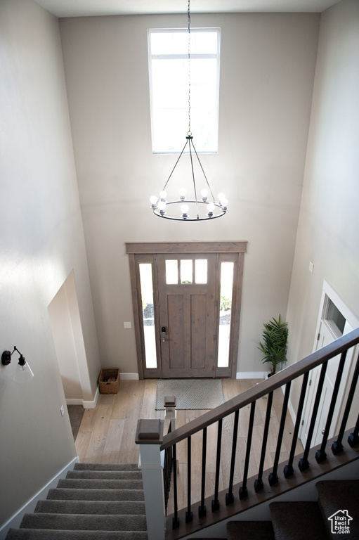 Foyer featuring a high ceiling, a chandelier, stairway, wood finished floors, and healthy amount of natural light