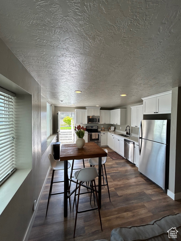 Dining space with dark wood-type flooring, a textured ceiling, and baseboards