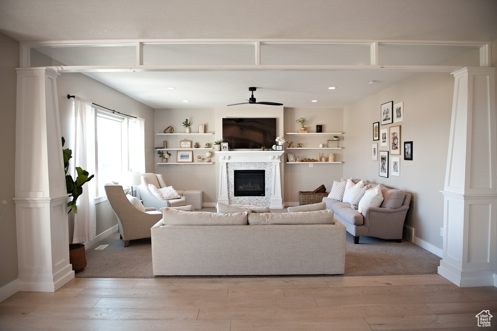Living room featuring ornate columns, a fireplace, light wood-style floors, and recessed lighting