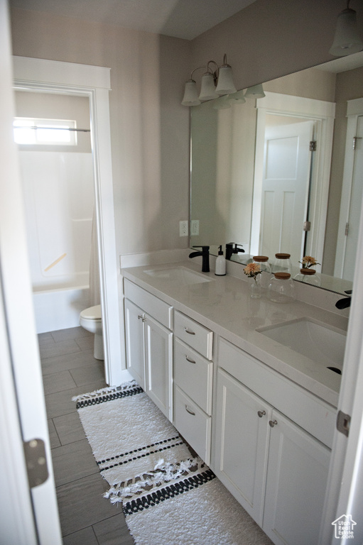 Bathroom with toilet, double vanity, and shower / bathtub combination