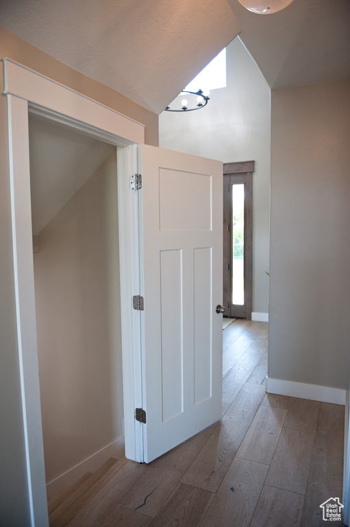 Hallway featuring hardwood / wood-style flooring, vaulted ceiling, and baseboards