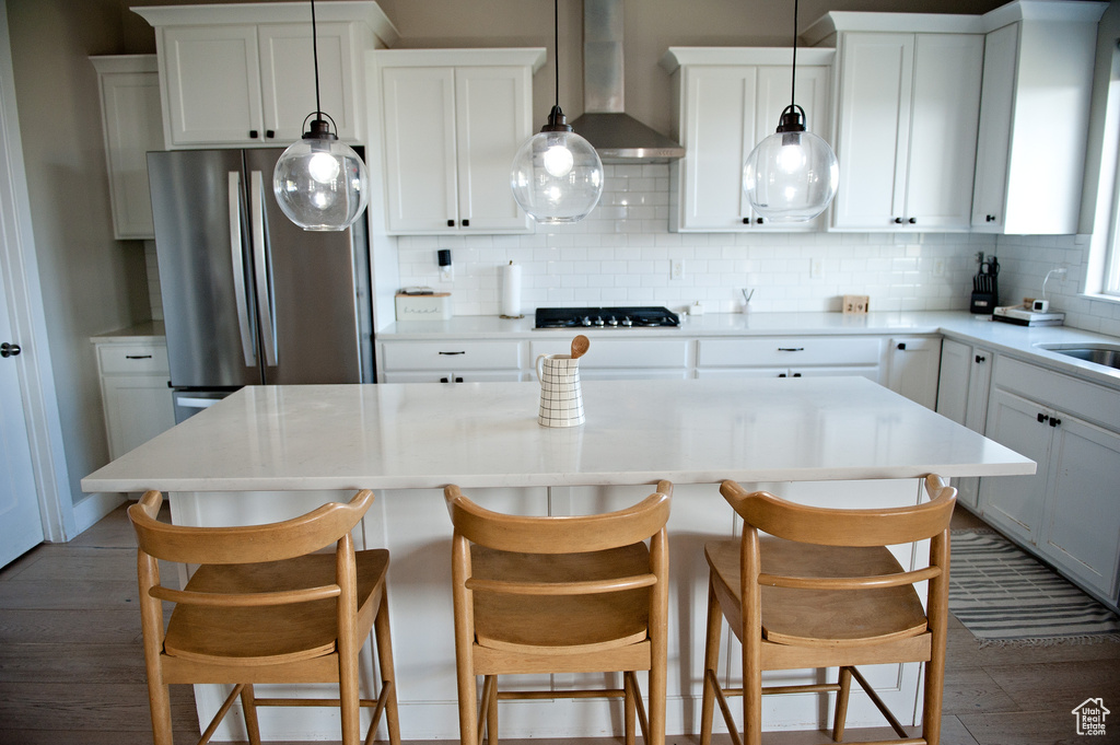 Kitchen featuring wall chimney exhaust hood, decorative backsplash, a kitchen island, dark wood-style floors, and black gas cooktop