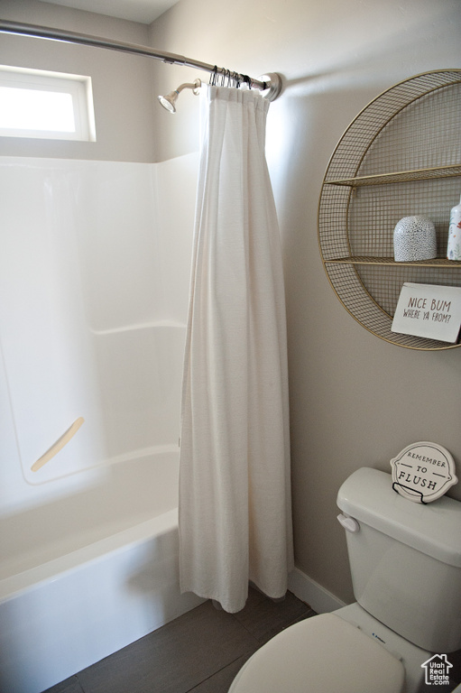 Full bath with toilet, shower / bath combo, and baseboards