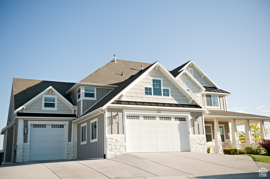 Craftsman house with stone siding, board and batten siding, a standing seam roof, concrete driveway, and metal roof
