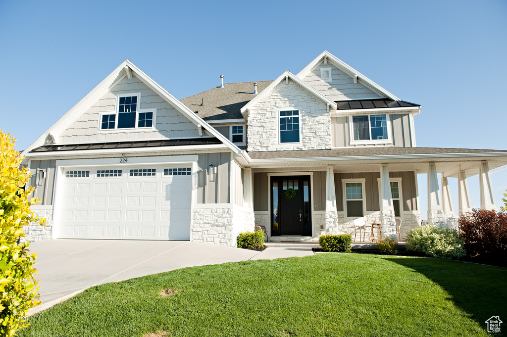 Craftsman-style home with a standing seam roof, stone siding, a porch, and board and batten siding