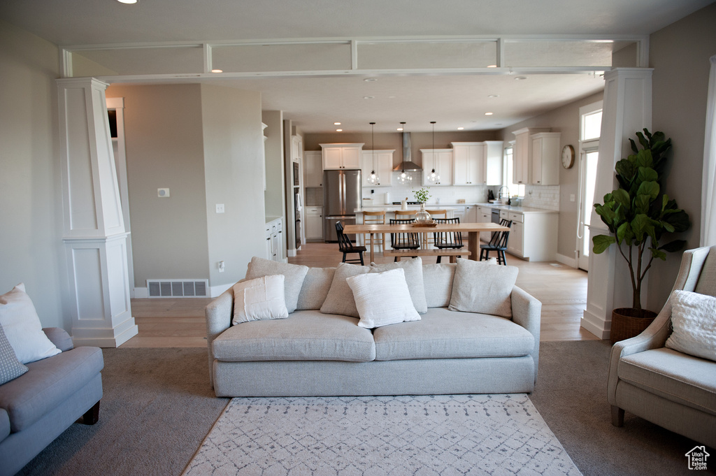 Living room with decorative columns, recessed lighting, and light wood-style floors