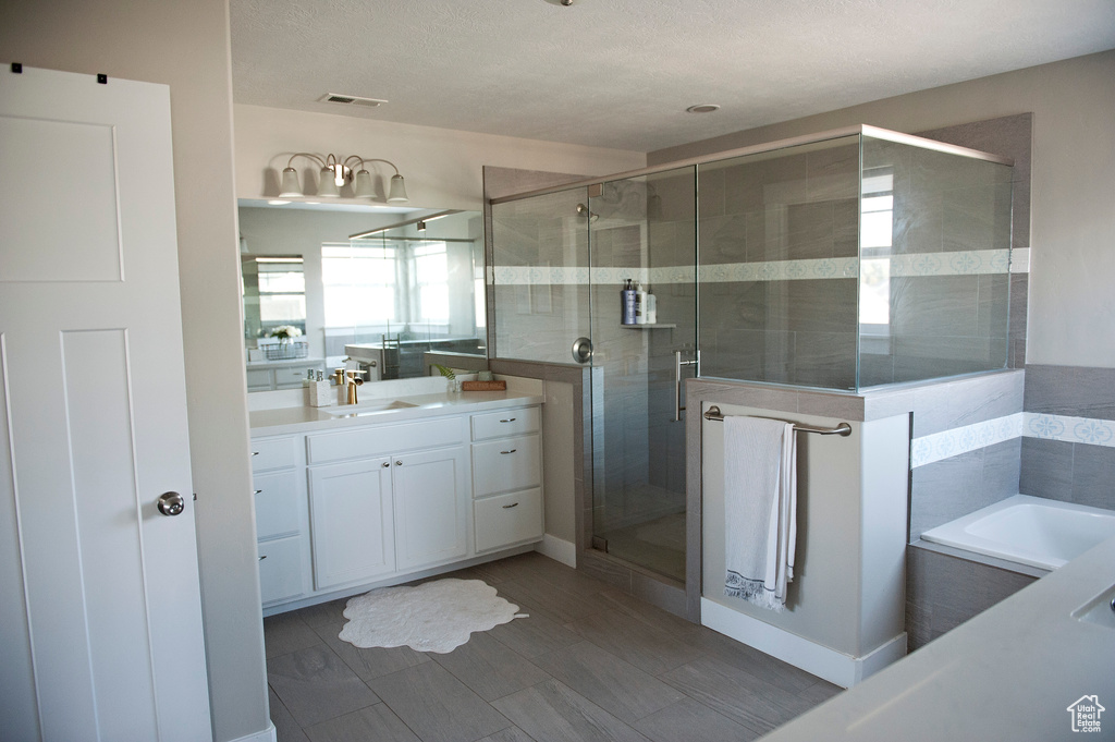 Full bathroom featuring a shower stall, vanity, a garden tub, and a textured ceiling