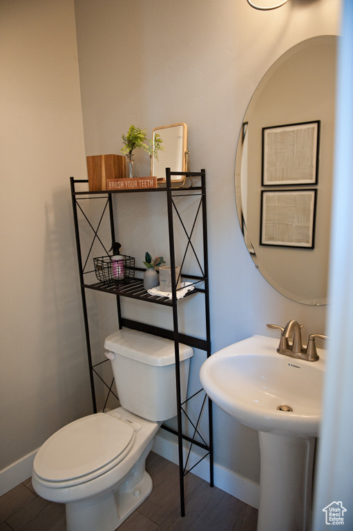 Bathroom with toilet, baseboards, and wood finished floors