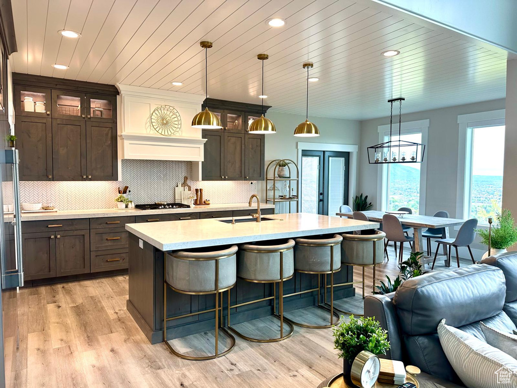 Kitchen featuring a sink, light countertops, recessed lighting, dark brown cabinets, and a breakfast bar area