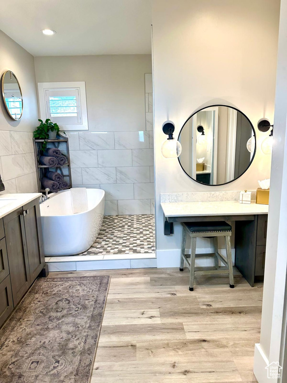 Bathroom with a freestanding tub, wood finished floors, and vanity