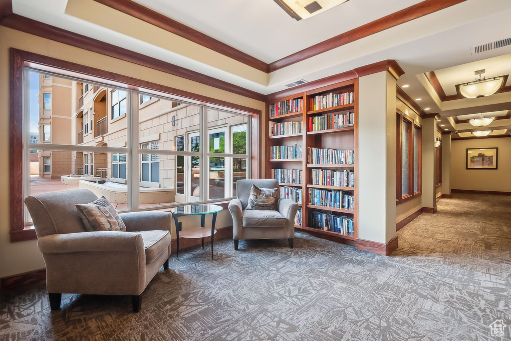 Living area with baseboards, carpet floors, a raised ceiling, built in features, and ornamental molding
