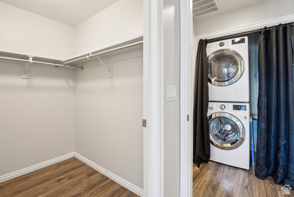 Washroom featuring stacked washer / dryer, wood finished floors, and baseboards