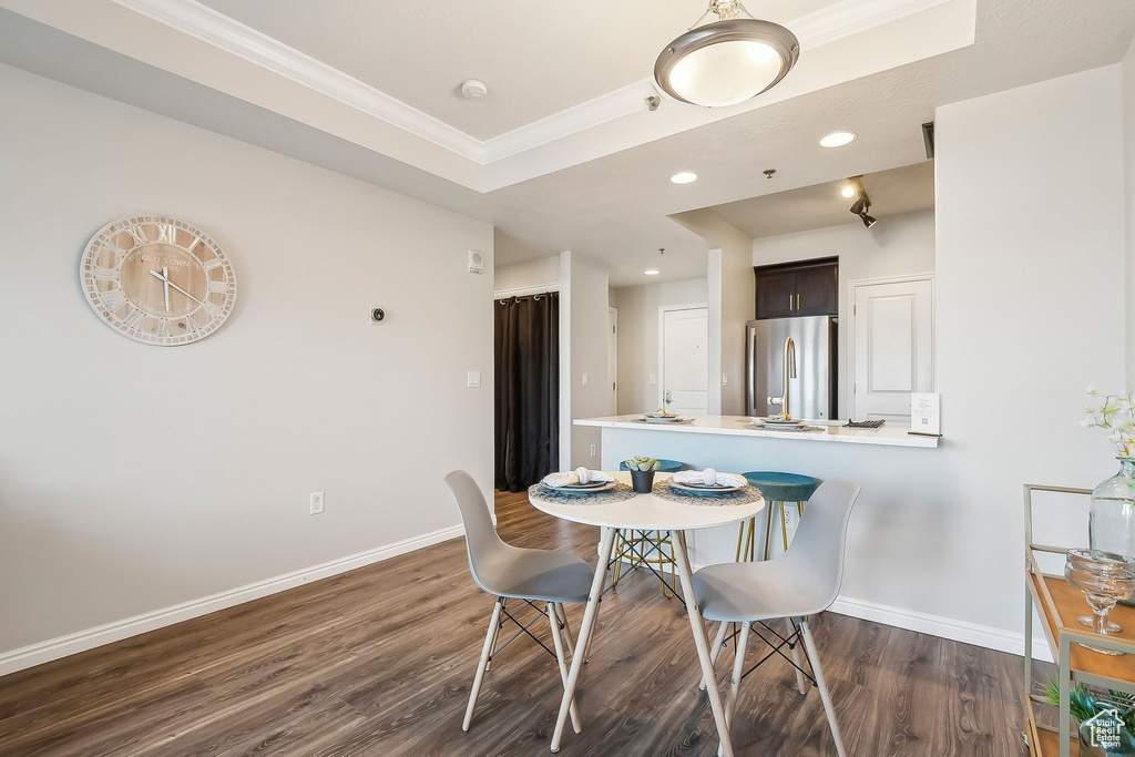 Dining area with dark wood finished floors, ornamental molding, baseboards, and recessed lighting
