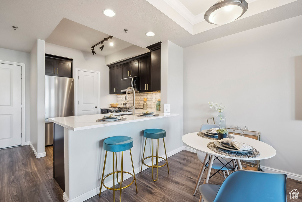 Kitchen featuring freestanding refrigerator, black microwave, dark wood-style floors, light countertops, and baseboards