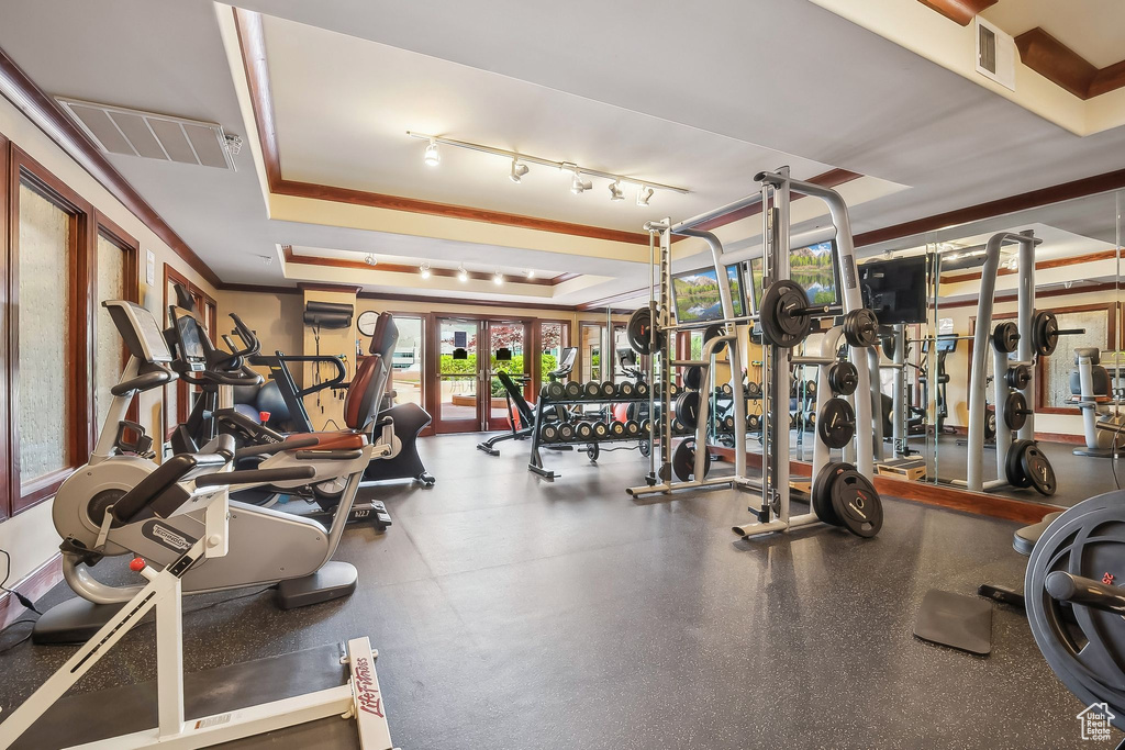 Gym featuring a tray ceiling and french doors