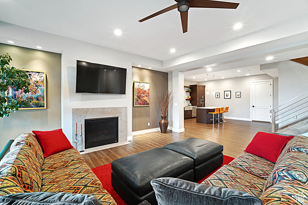 Living room with a ceiling fan, wood finished floors, baseboards, stairs, and recessed lighting