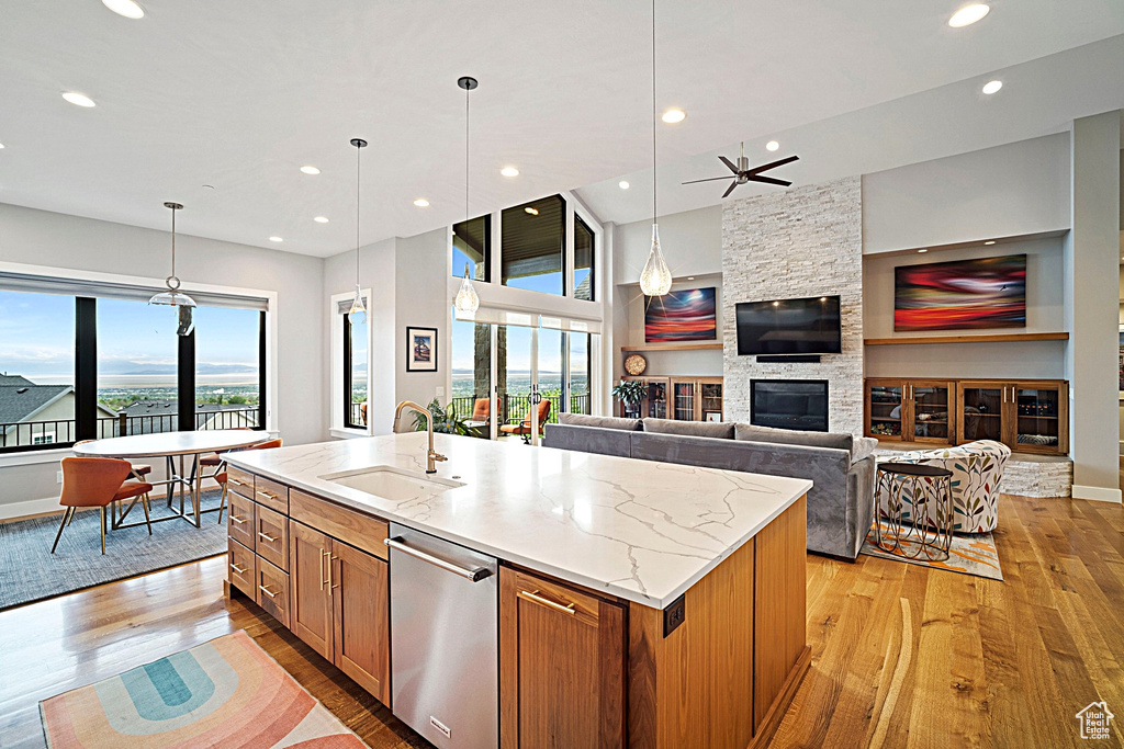 Kitchen featuring a sink, light wood-style flooring, brown cabinetry, stainless steel dishwasher, and recessed lighting