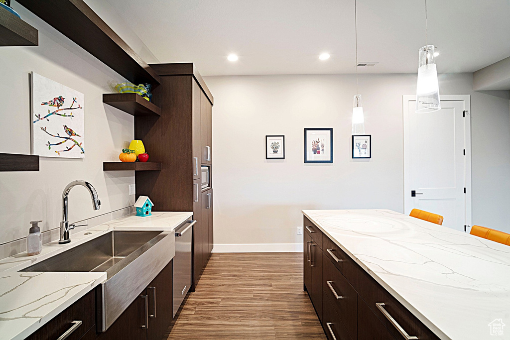 Kitchen with open shelves, a sink, wood finished floors, dark brown cabinetry, and recessed lighting
