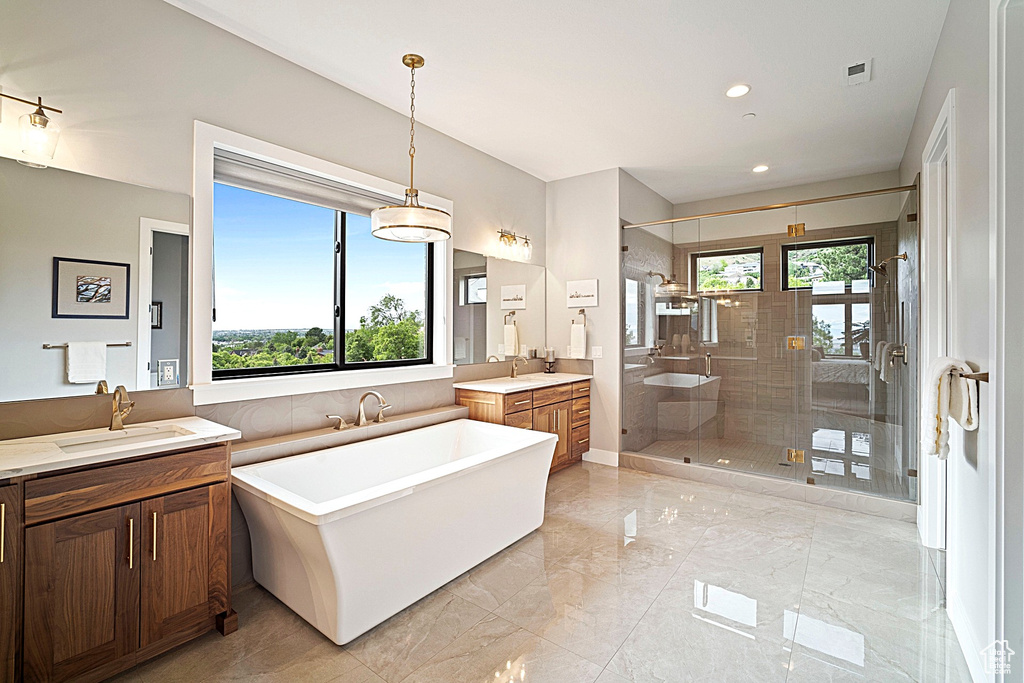 Bathroom with a stall shower, marble tiled flooring, two vanities, a freestanding bath, and recessed lighting