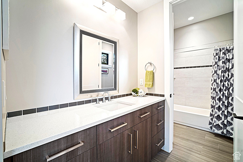 Full bathroom with vanity, shower / bath combo with shower curtain, and wood finished floors