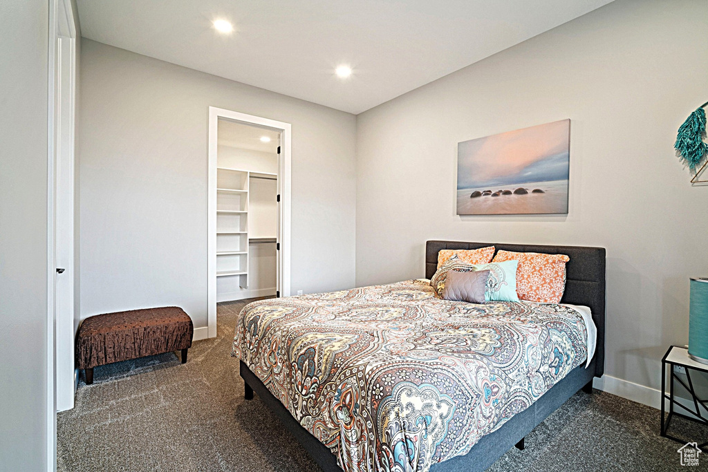 Bedroom with baseboards, recessed lighting, carpet floors, and a walk in closet