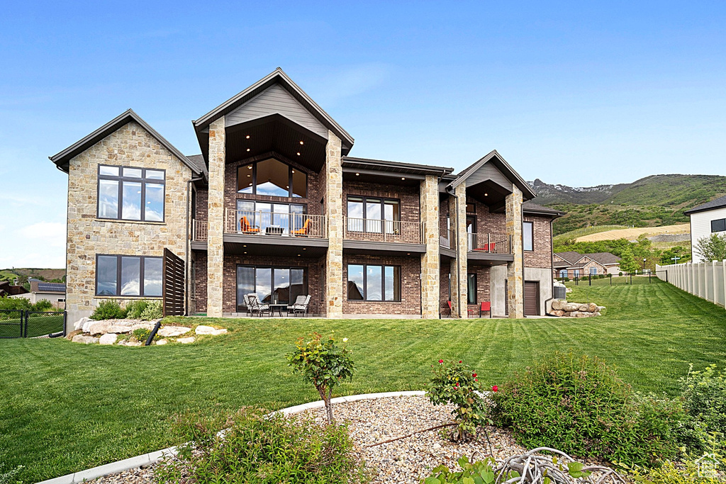 Rear view of house with a balcony, brick siding, and a mountain view
