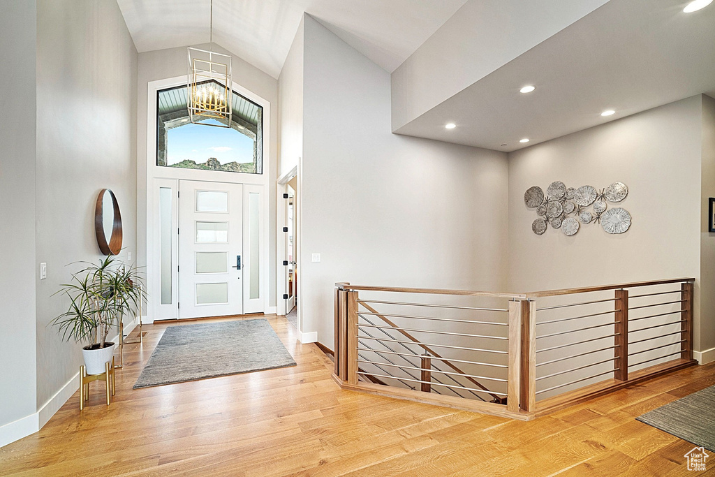 Entrance foyer featuring a chandelier, wood finished floors, baseboards, high vaulted ceiling, and recessed lighting