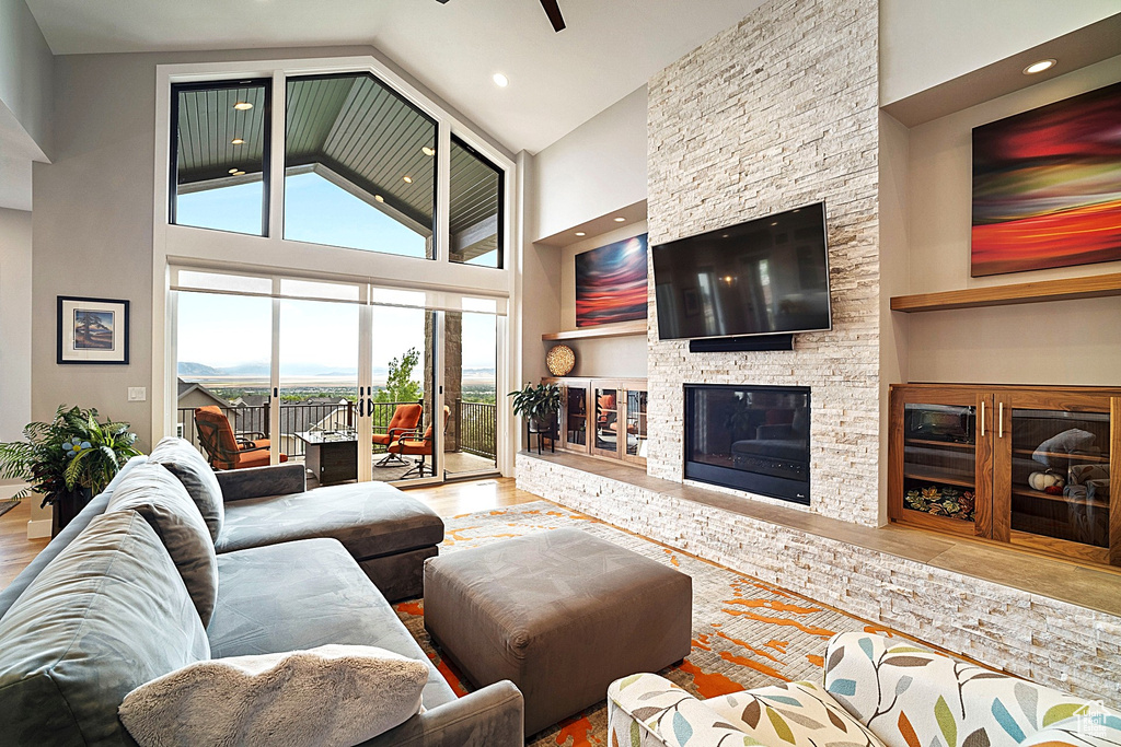 Living area with high vaulted ceiling, a fireplace, wood finished floors, and recessed lighting